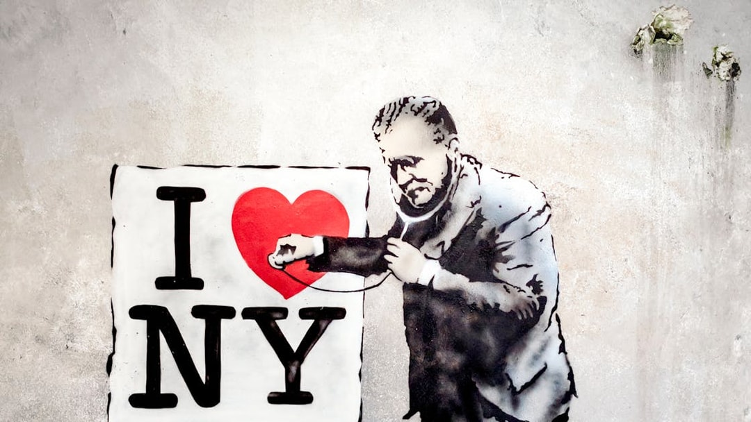 Street art of a man examining "I Love NY" sign with a stethoscope at Banksy Museum.