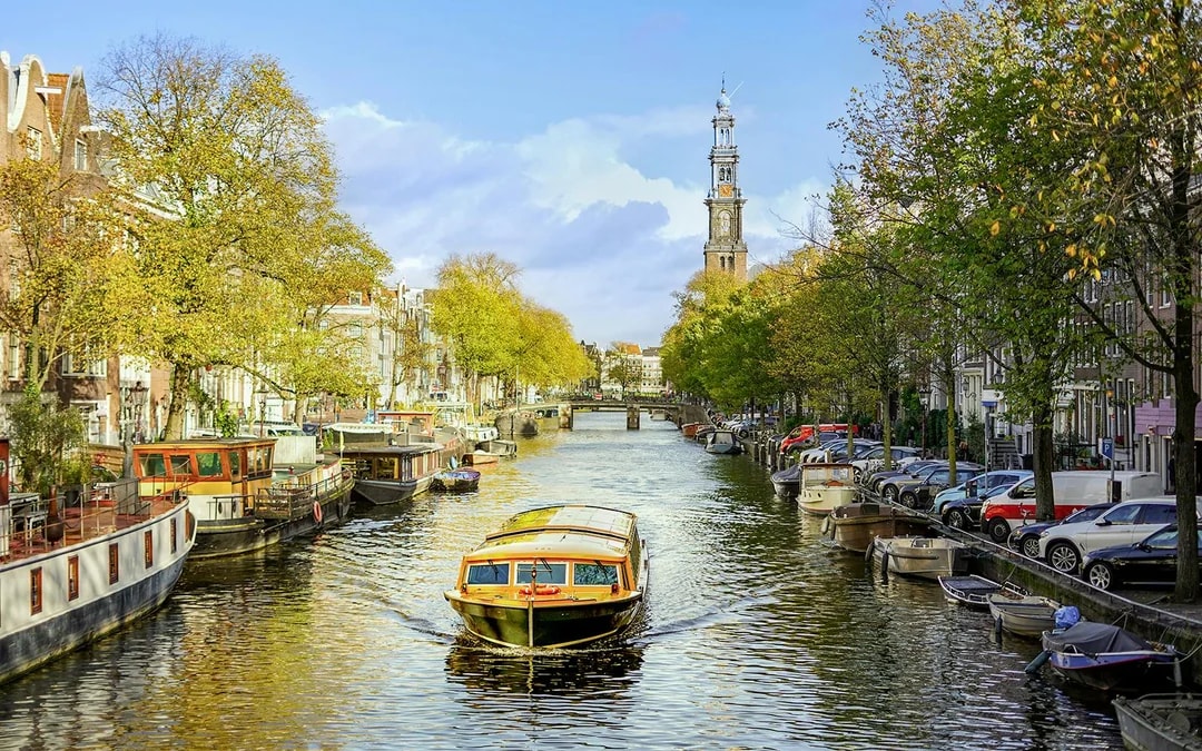 Canal cruise boat on Amsterdam's canal with Westerkerk in the background.