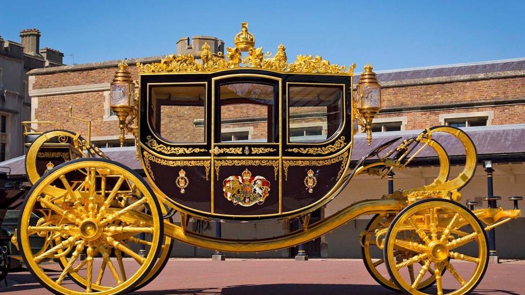 Golden royal carriage at Buckingham Palace courtyard.