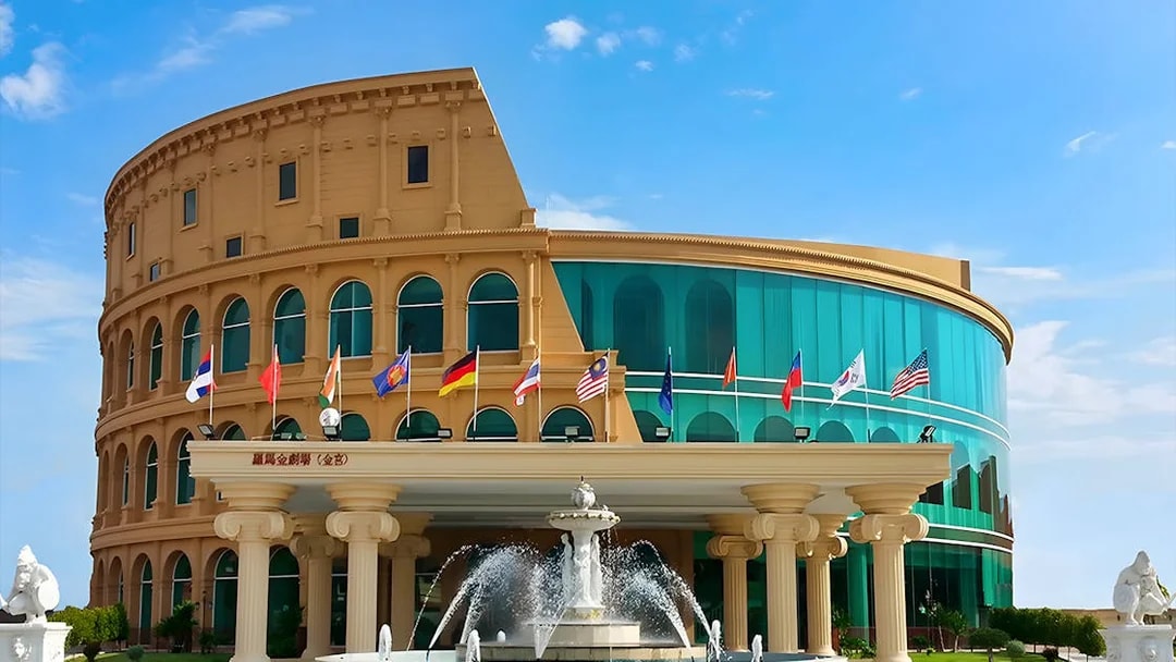 Colosseum Show Pattaya building with international flags and fountain.