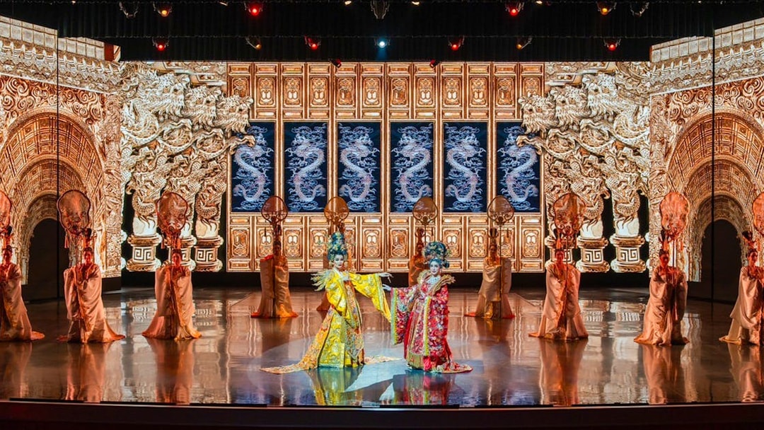 Traditional Chinese performance with ornate costumes and dragon backdrop at The Colosseum.