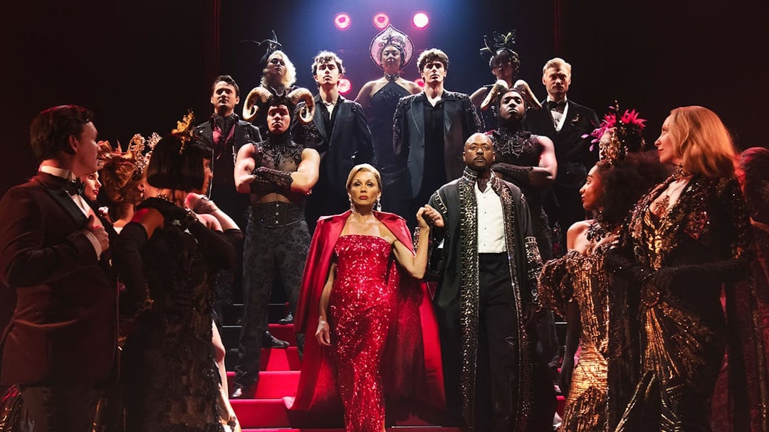 Theater cast in elaborate costumes on stage for The Devil Wears Prada musical.