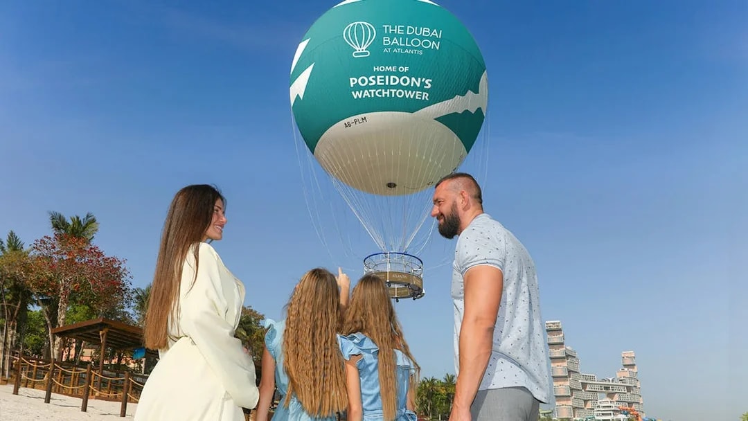 Family observing The Dubai Balloon at Atlantis with resort in background.