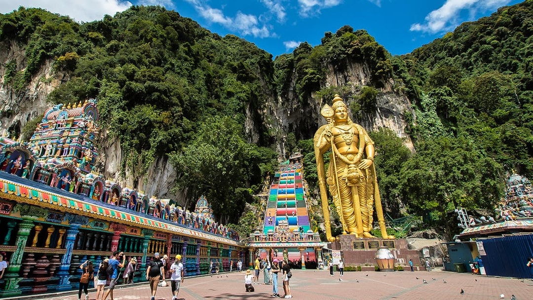 Batu Caves entrance with golden Murugan statue and colorful temple, Kuala Lumpur.