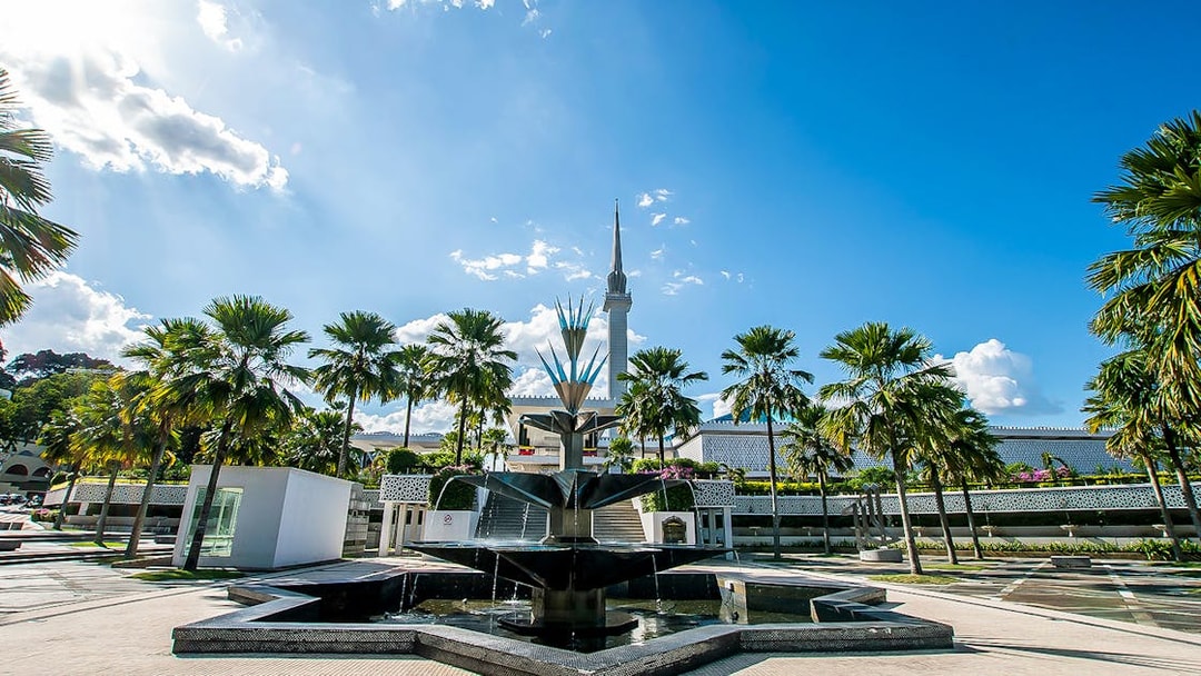 Fountain and palm trees at the National Mosque, Kuala Lumpur, part of the Great KL City Tour.