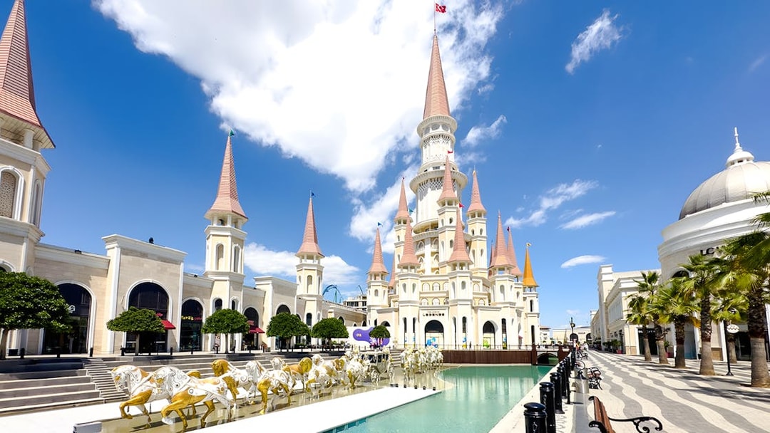 Land of Legends Themepark castle with spires and horse statues by a water feature.