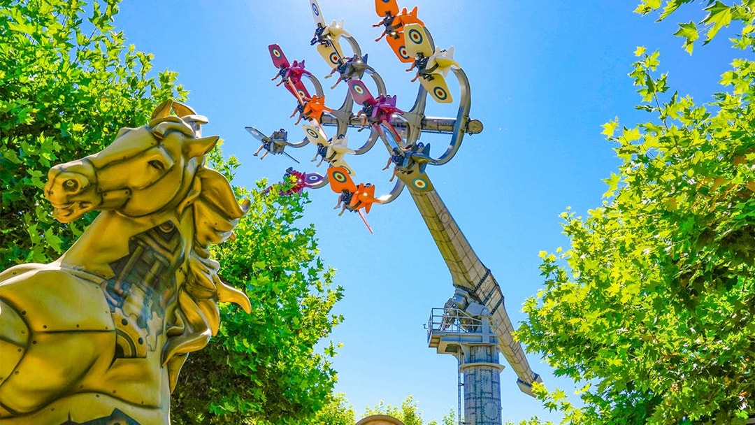 Sky Fighter ride at The Land of Legends theme park with colorful planes and a golden horse statue.