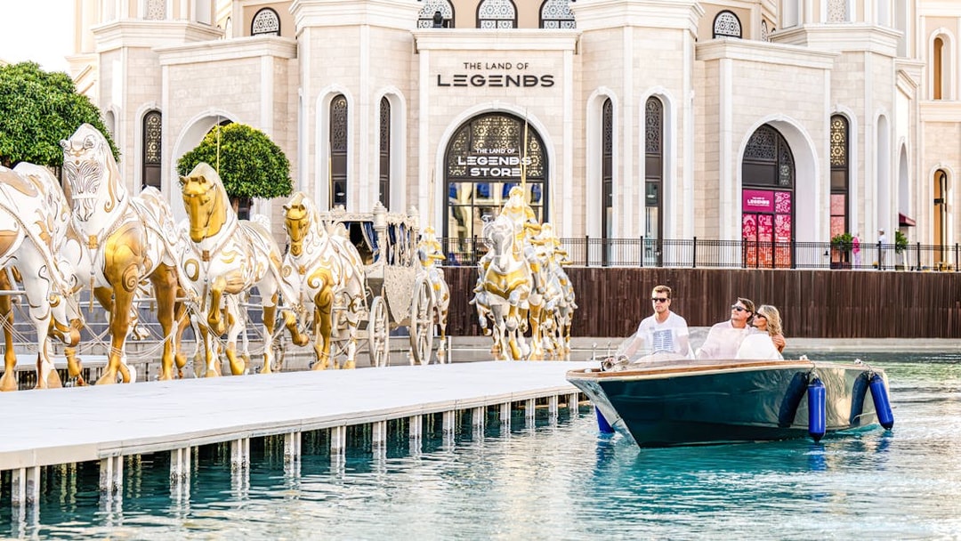 Couple enjoying a boat ride at The Land of Legends theme park with golden horse statues.