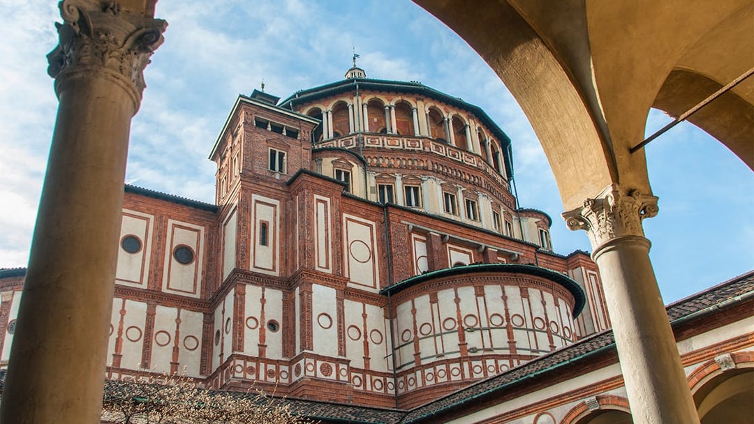Santa Maria delle Grazie church exterior in Milan, Italy, viewed through archway.