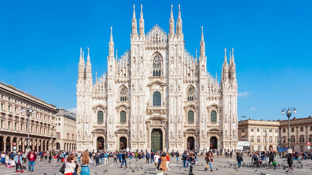 Crowd in front of Milan's Duomo Cathedral on a sunny day.