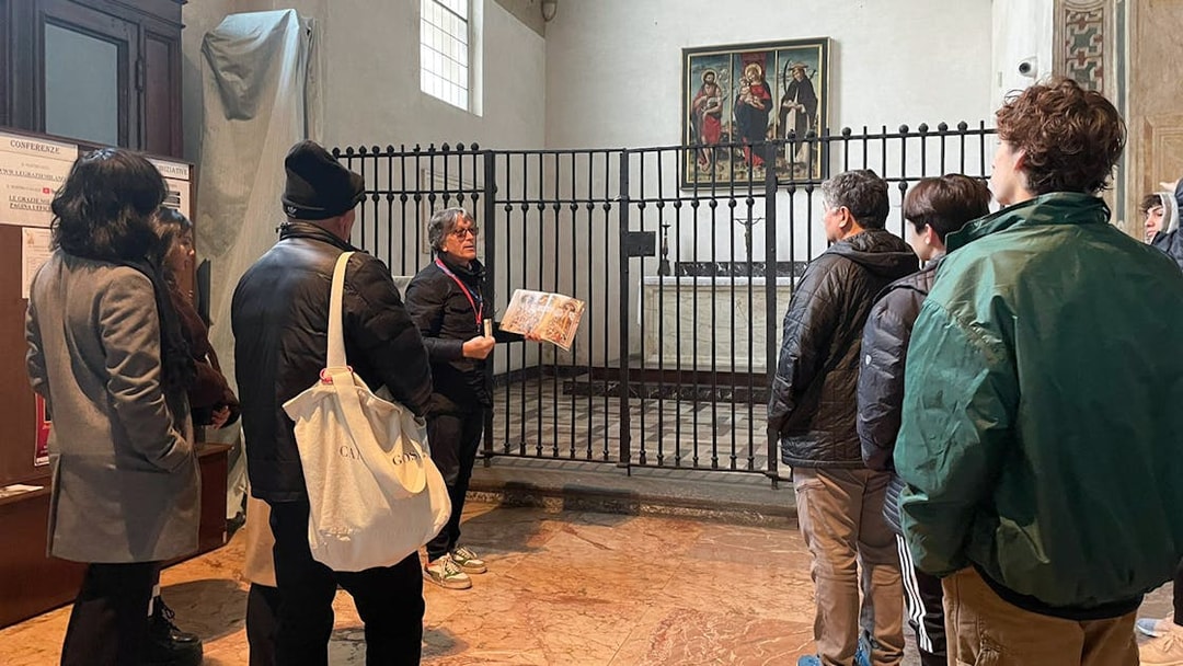 Tour guide explaining a painting to tourists in a historic building.