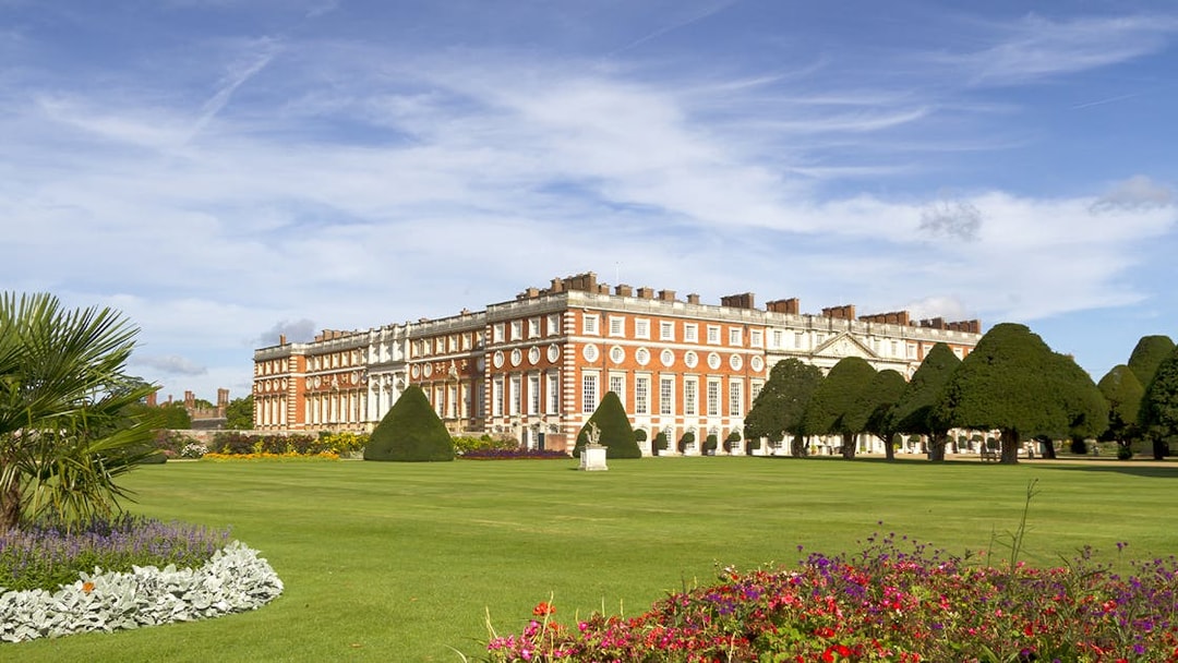 Hampton Court Palace with manicured gardens and colorful flowers, London.