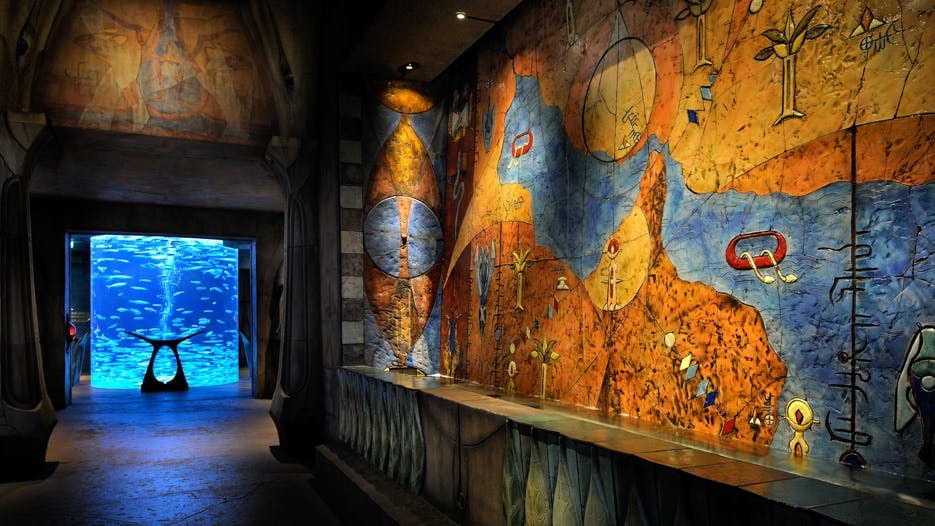 Atlantis The Lost Chambers Aquarium entrance with vibrant mural and fish tank.