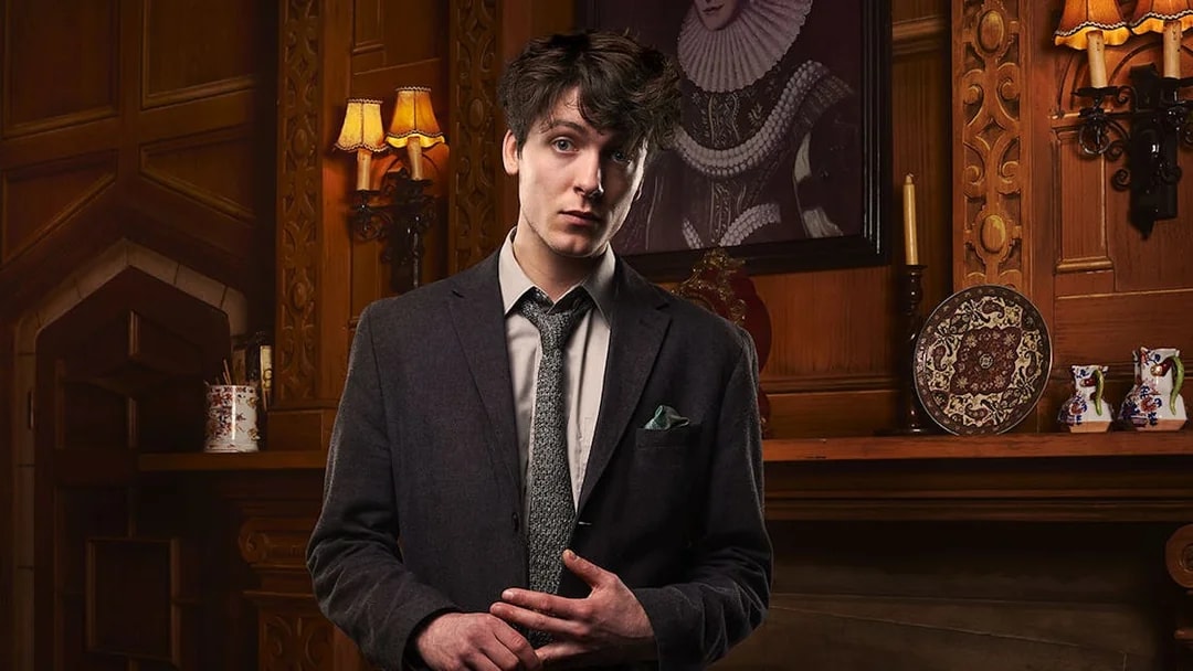 Man in a suit standing in a vintage room with ornate wood paneling, related to The Mousetrap.