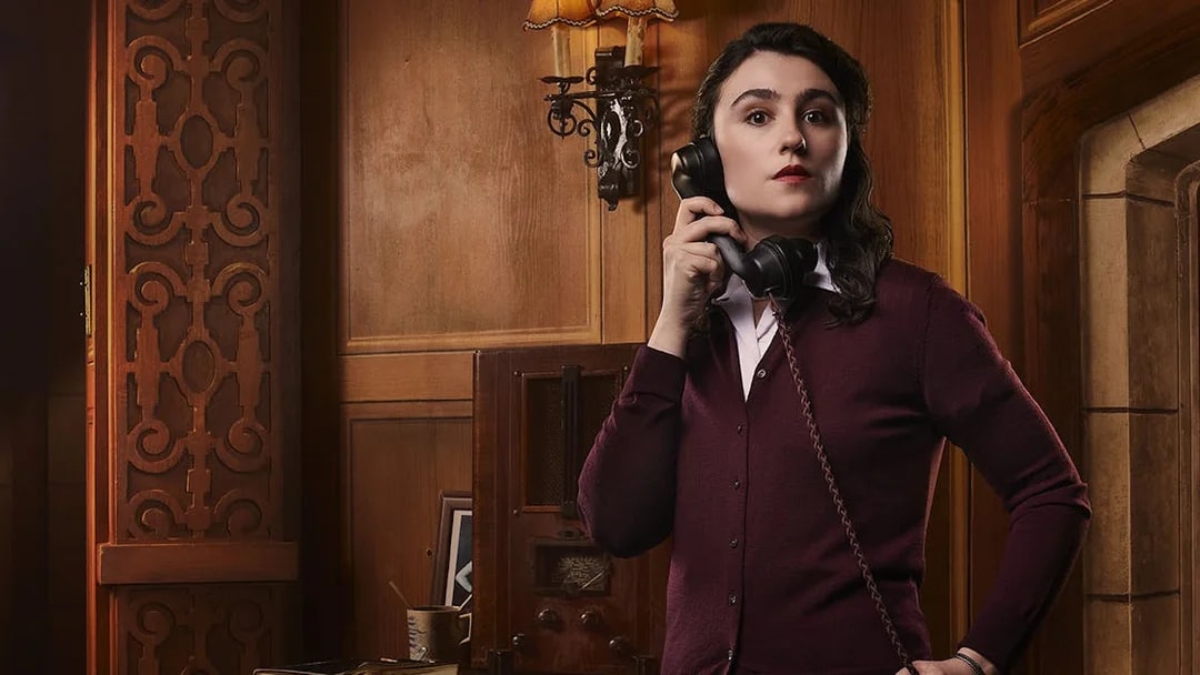 Person holding a vintage telephone in a wood-paneled room, related to The Mousetrap.