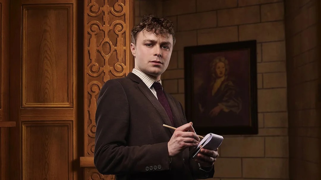 Man in suit taking notes inside a theater setting for The Mousetrap play.