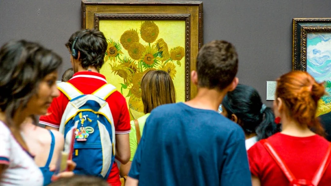Visitors viewing Van Gogh's Sunflowers painting in a museum.
