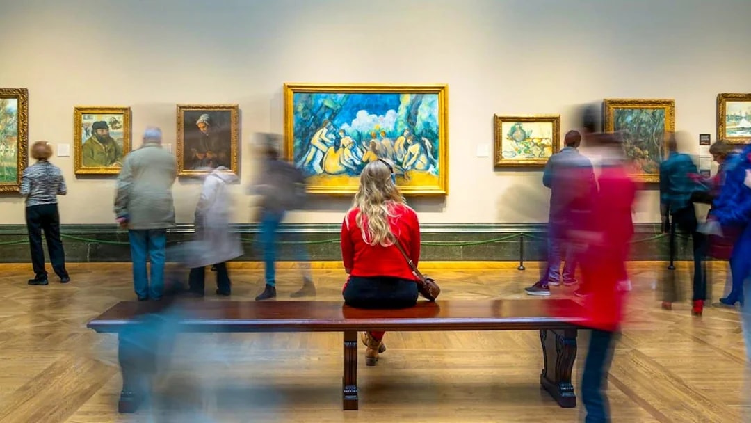 Woman sitting on bench viewing artwork at National Gallery guided tour.