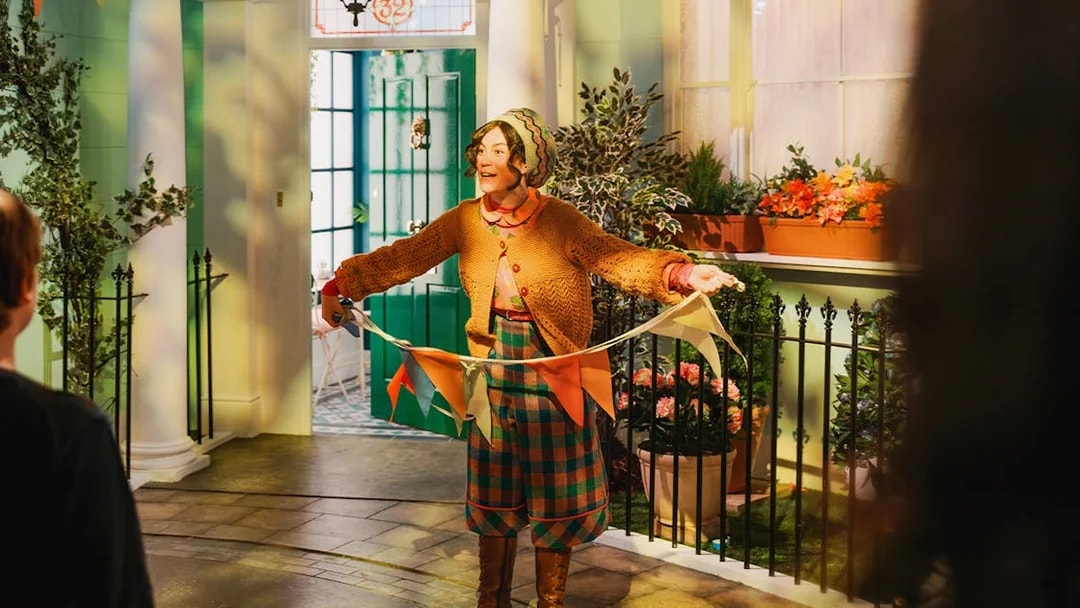 Tour guide holding colorful flags at The Paddington Bear Experience in London.