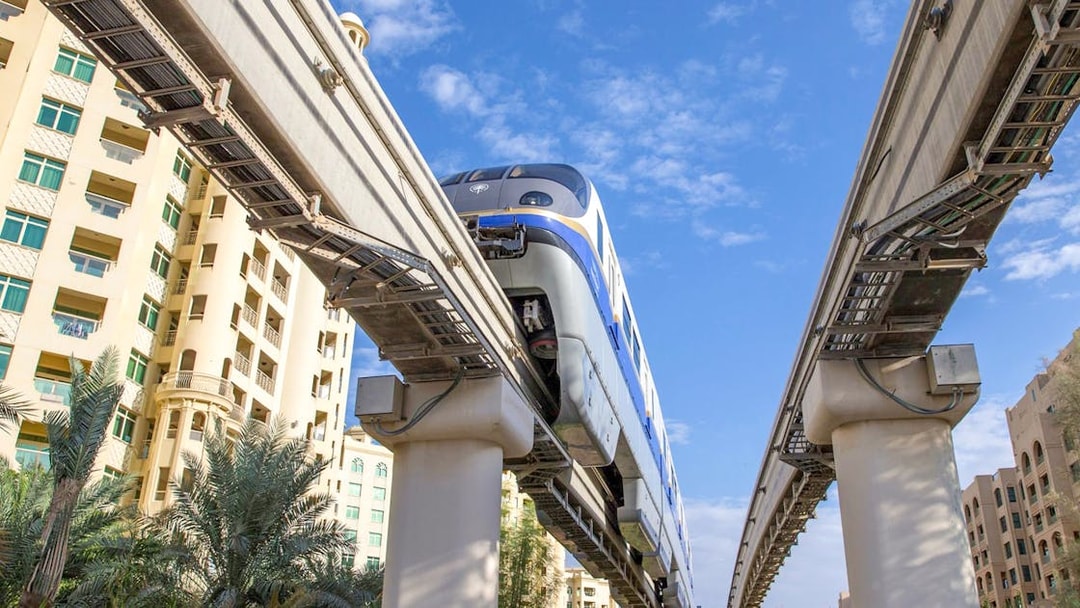 Palm Jumeirah Monorail passing between residential buildings in Dubai.