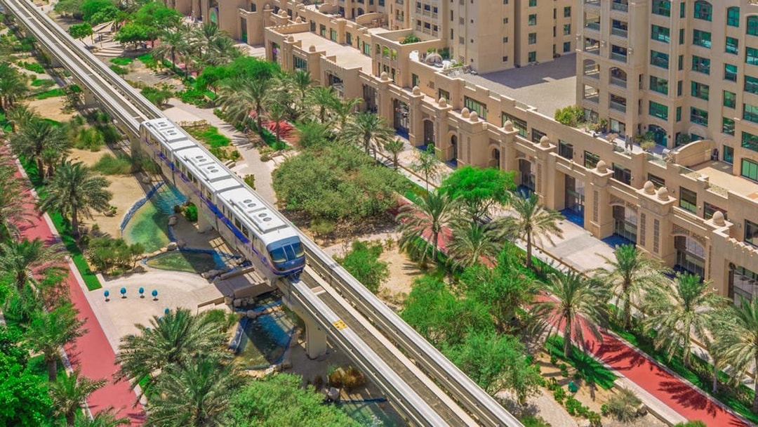 Palm Jumeirah Monorail passing through lush greenery and modern architecture in Dubai.