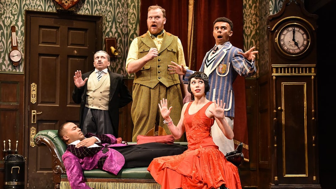 Actors performing a comedic scene in "The Play That Goes Wrong" on stage.