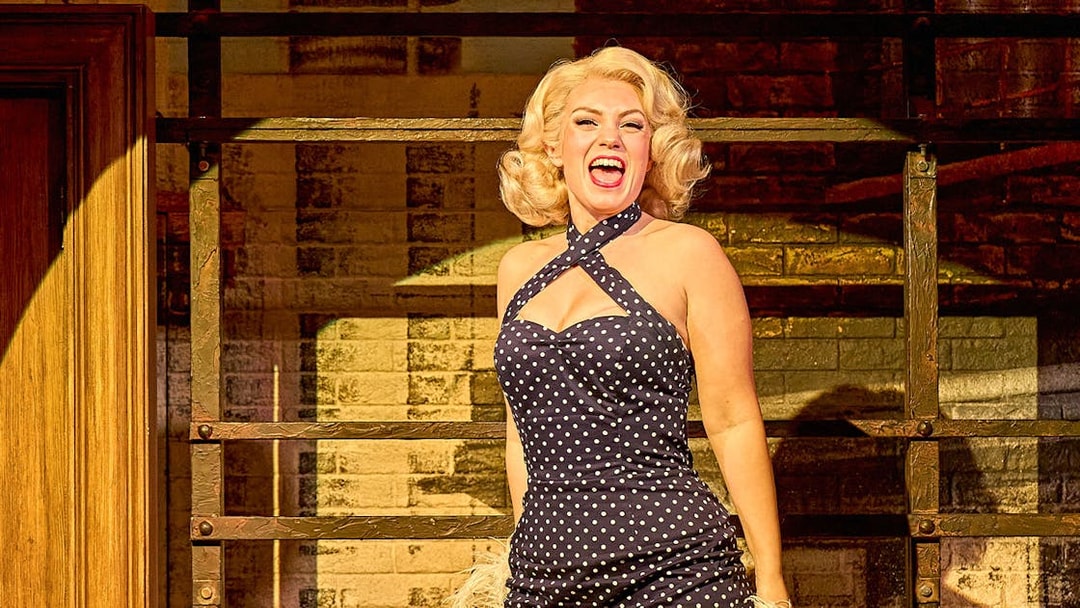 Performer in polka dot dress on stage during "The Producers" musical.