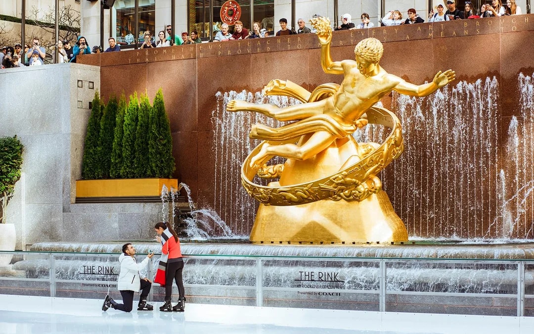 Tourists ice skating at The Rink with Prometheus statue in the background.