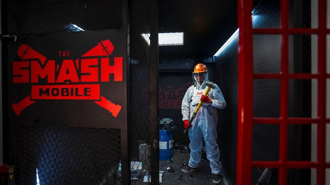 Tourist holding sledgehammer inside Smash room experience.