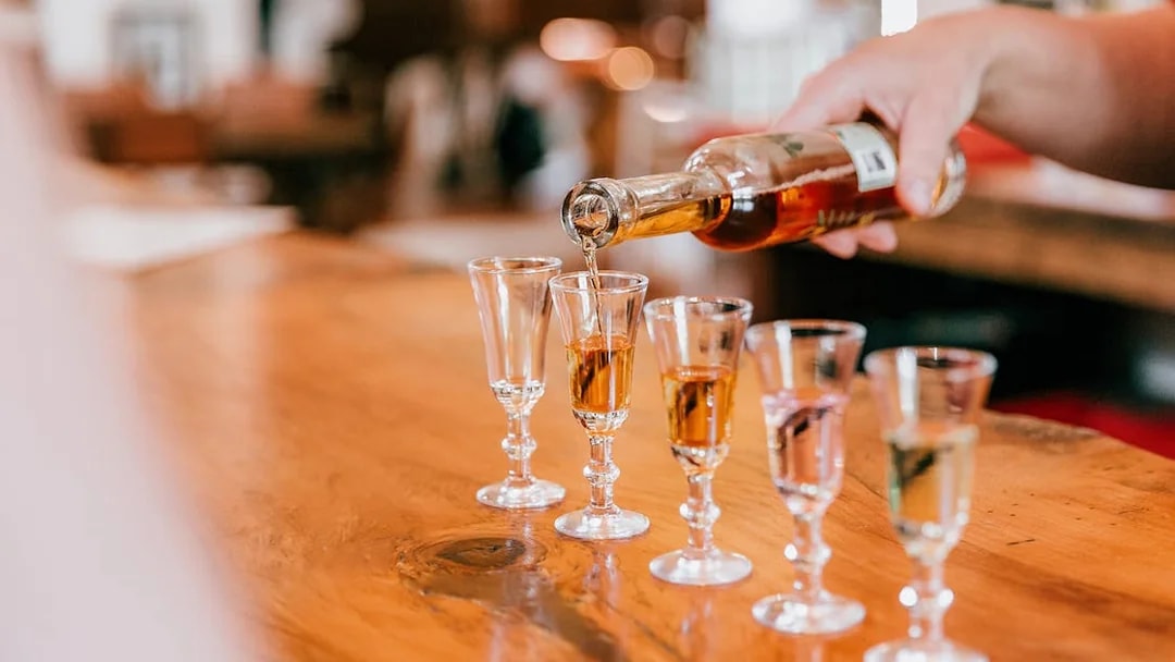 Pouring spirits into glasses on a wooden table at Tamborine Mountain tasting tour.