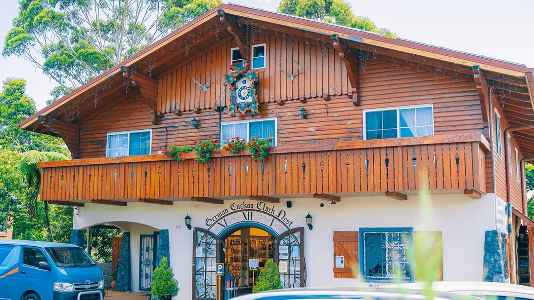 German Cuckoo Clock Nest on Tamborine Mountain, showcasing wooden architecture and vibrant flowers.