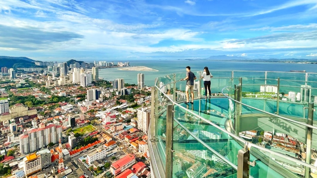 Couple enjoying the view from The Top, Penang's glass skywalk overlooking the city and sea.