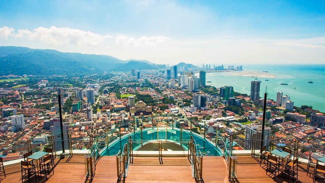 Skywalk view from The Rainbow Walk at The Top, Penang, overlooking cityscape and coastline.