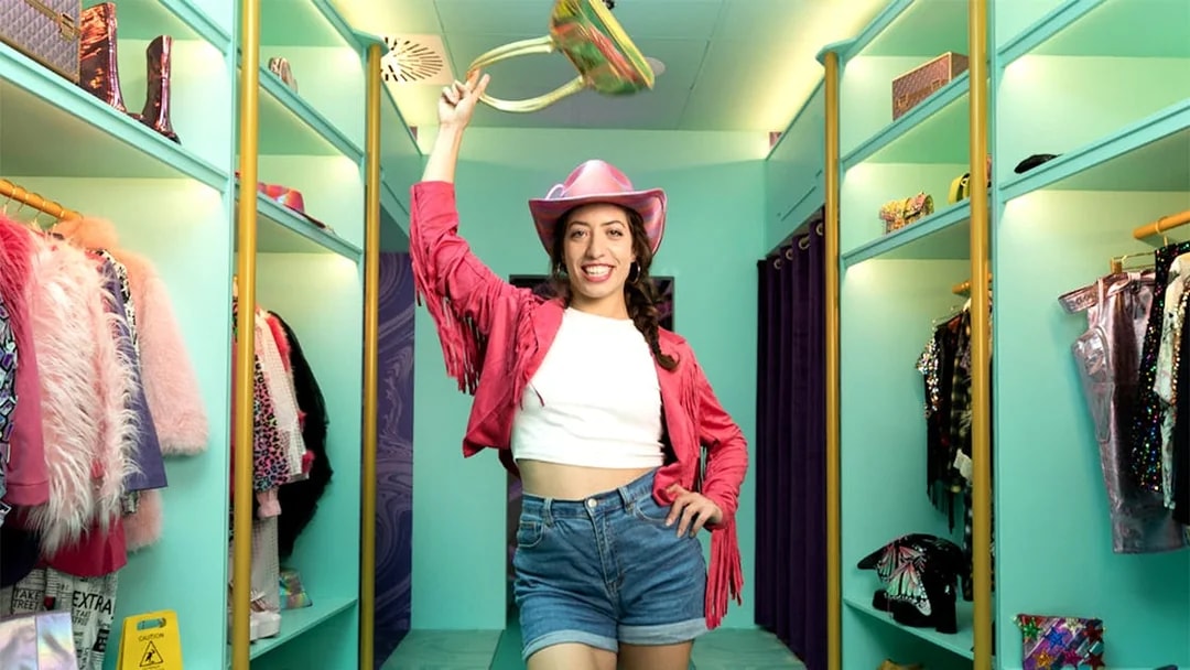 Person in a pink cowboy hat and jacket posing in a colorful wardrobe room at The Upside Down Berlin.