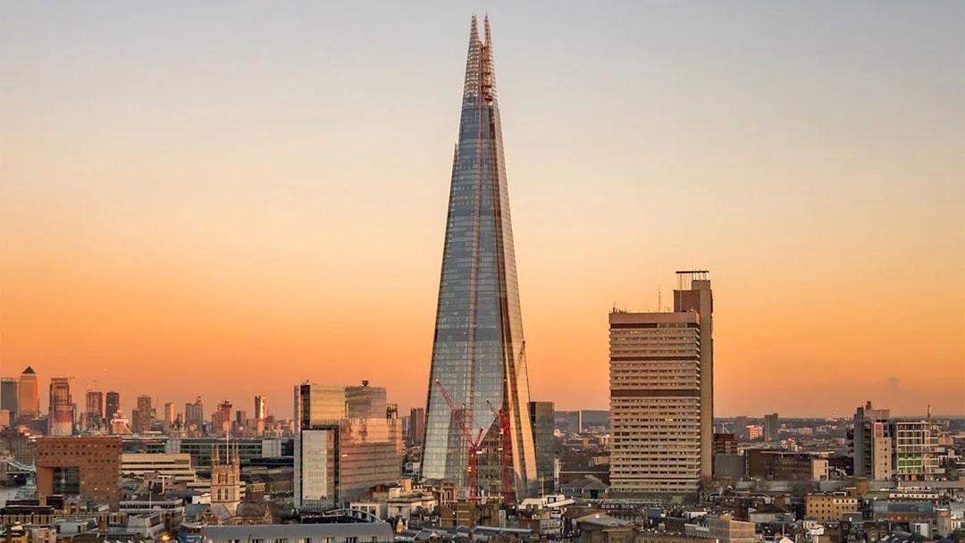 View of the Shard in London at sunset with city skyline.