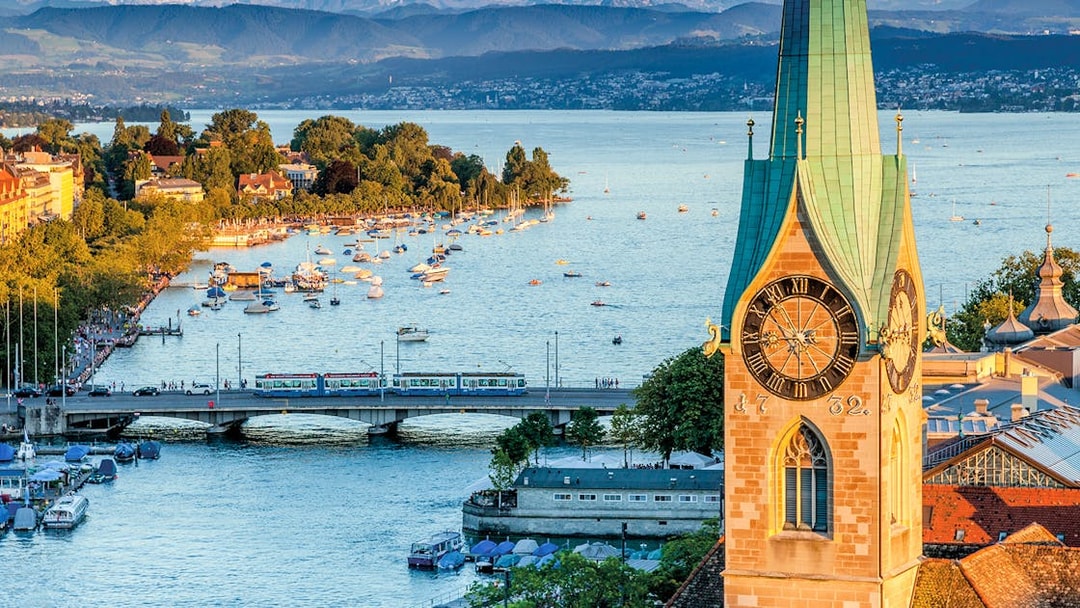 Zurich cityscape with Lake Zurich, boats, and historic clock tower.