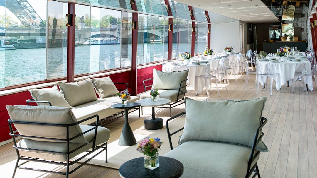 Rooftop seating area on a Parisian boat cruise with tables set for brunch.