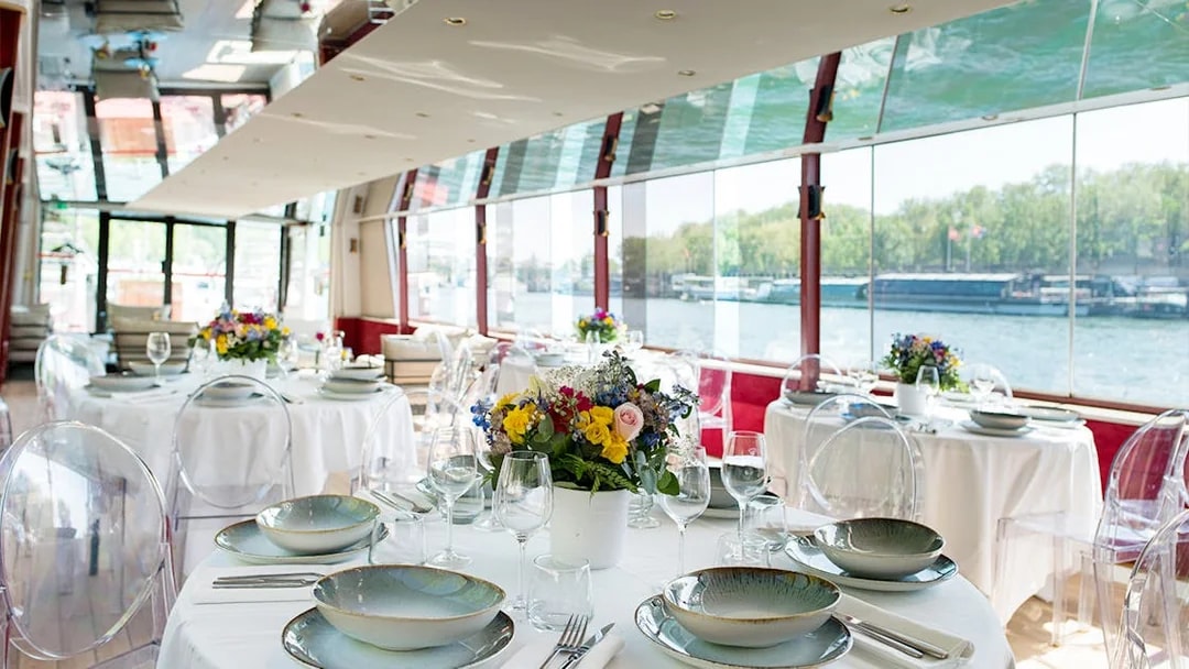 Elegant dining setup on a Parisian boat cruise with river views.