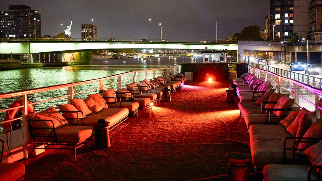 Seine River dinner cruise deck with seating, Paris city lights in background.