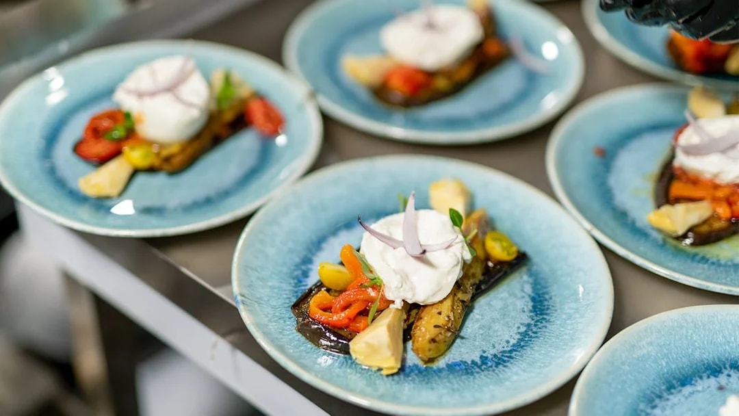 Italian appetizer with burrata and roasted vegetables on a blue plate, Paris dinner cruise.