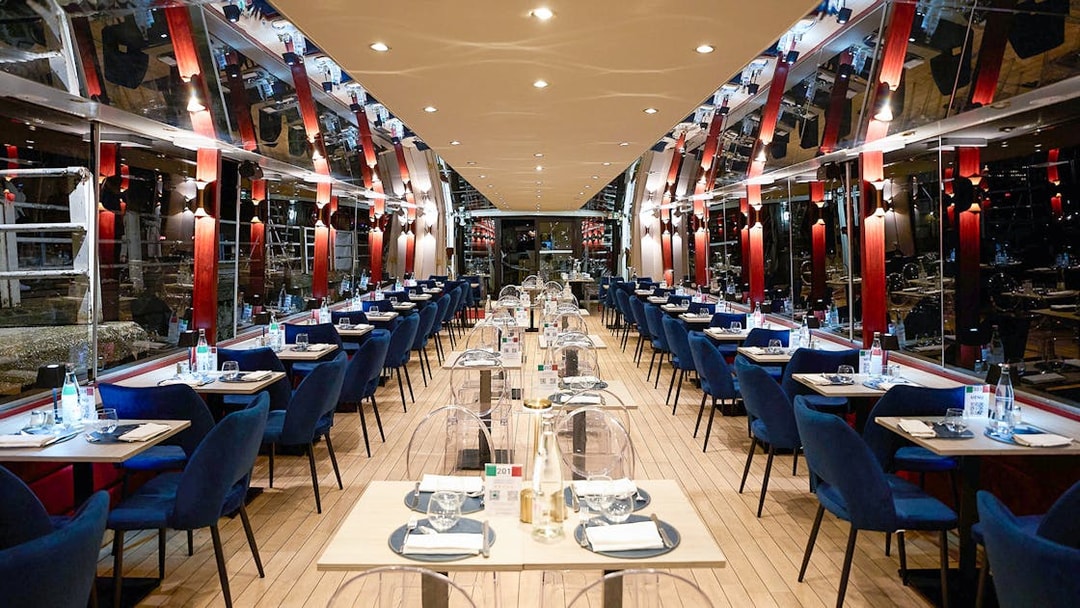 Seine River dinner cruise interior with tables set for an Italian menu experience.