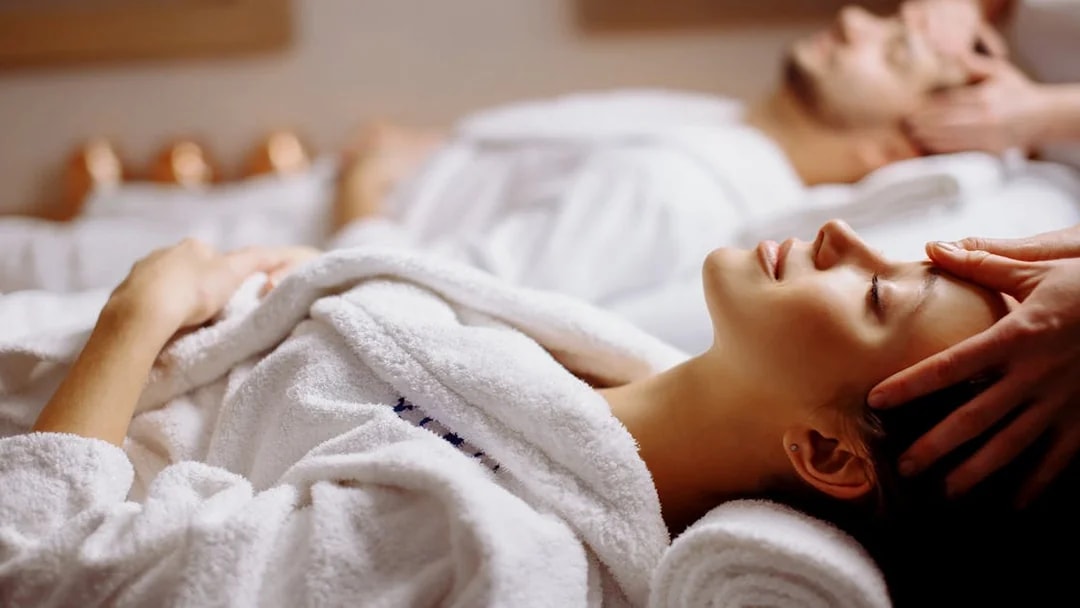 Couple receiving head massages at Spa in Therme Bucuresti.