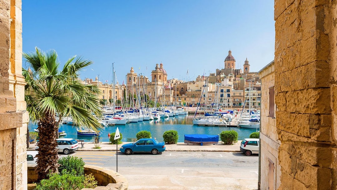 Boats docked in a marina with historic buildings in the Three Fortified Cities, Malta.