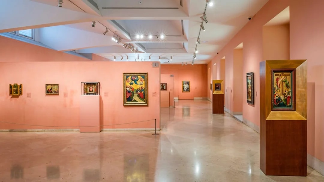 Thyssen Bornemisza Museum gallery with diverse paintings on pink walls.