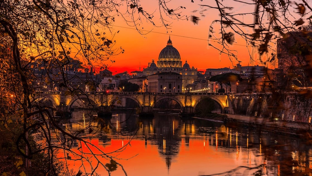 Sunset view of St. Peter's Basilica and Tiber River in Rome during an aperitif cruise.