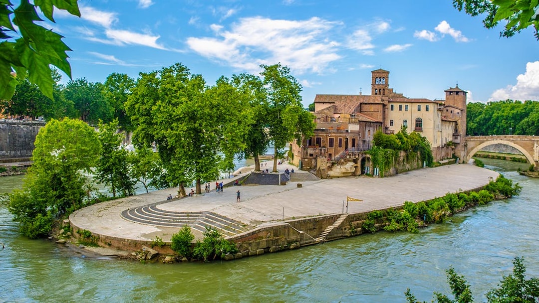 Tiber Island with historic buildings and trees, Rome, viewed from the Tiber River.