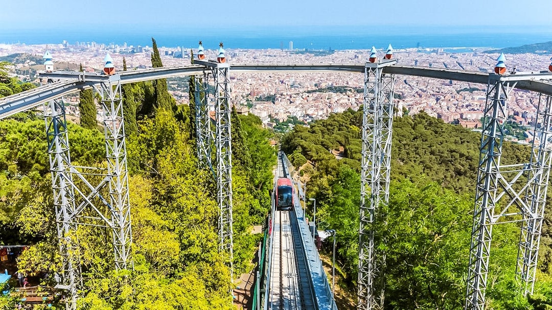Funicular ascending Tibidabo Amusement Park with Barcelona cityscape in the background.
