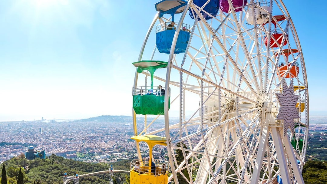 Ferris wheel at Tibidabo Amusement Park overlooking Barcelona cityscape.