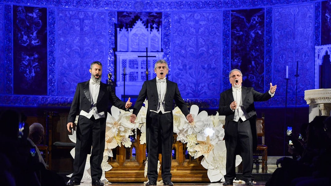 Opera singers performing on stage at a nighttime event with ornate blue backdrop.