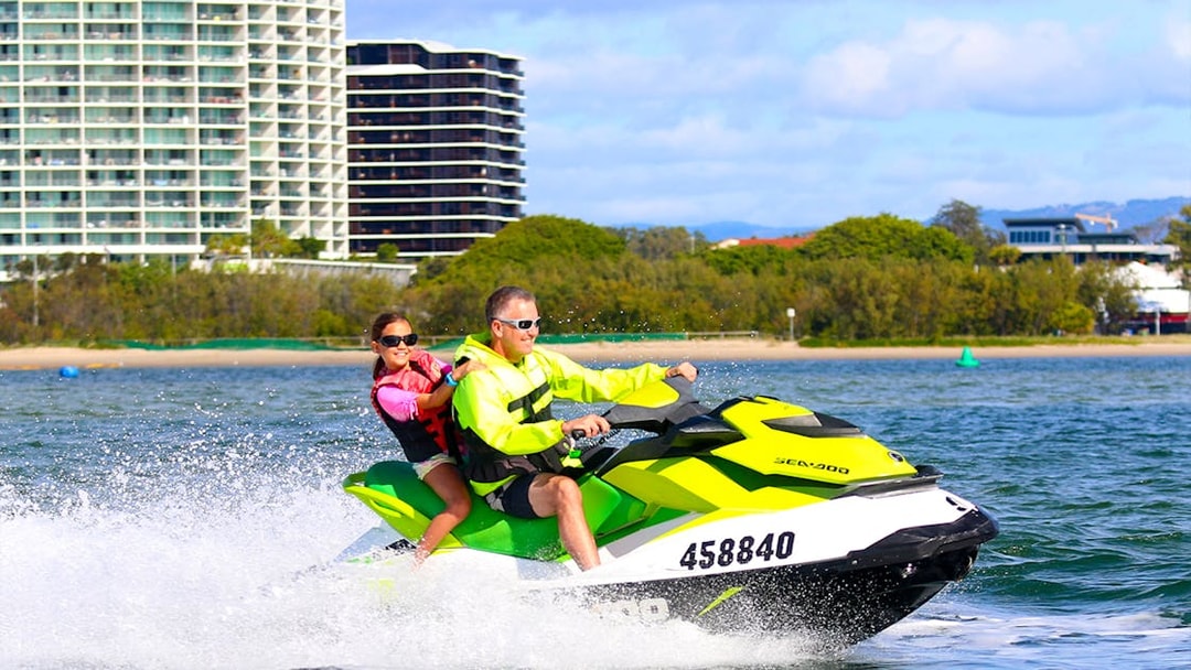 Jet skiing near city waterfront during Jet Ski & Parasail Experience.